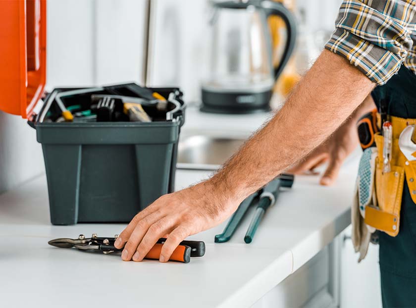 A man holding a toolbox in one hand and a tool in the other